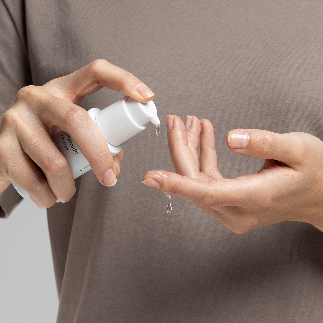 Eine Person pumpt eine transparente Flüssigkeit aus einer weißen Flasche auf ihre Fingerspitzen.