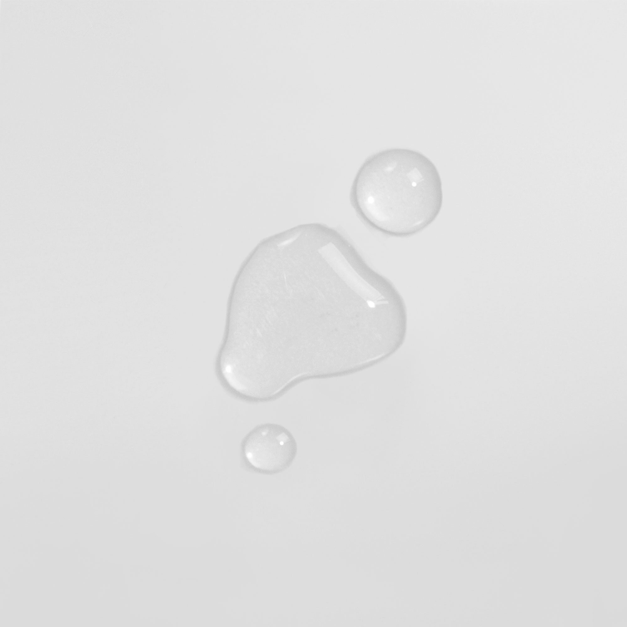 Drei Wassertropfen auf einer weißen Oberfläche.