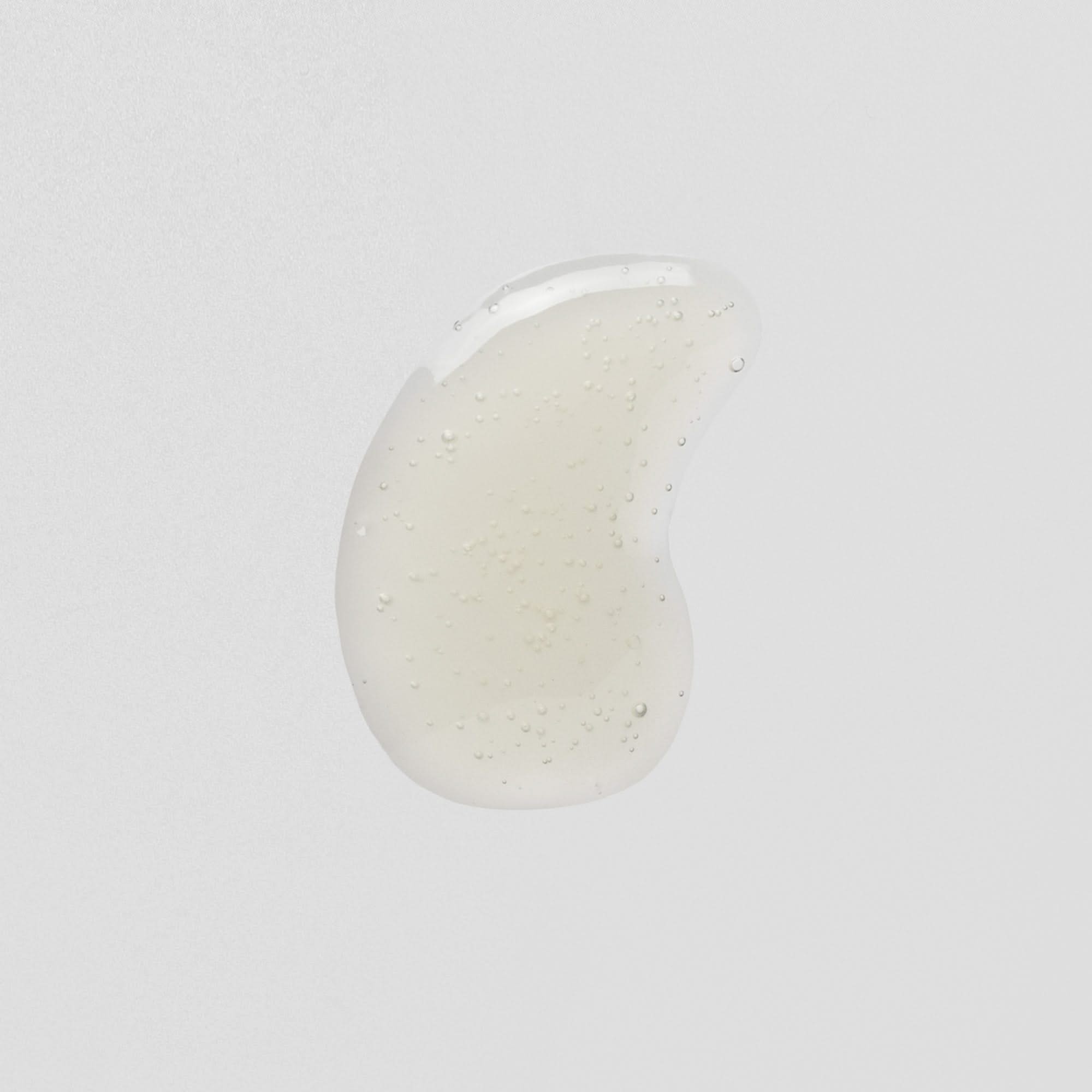 Transparenter Tropfen Gel mit kleinen Luftblasen auf weißem Hintergrund.