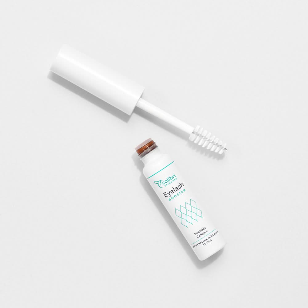 Flasche mit Wimpernbooster und Bürstenapplikator auf hellem Hintergrund, Etikett "Eyelash Booster".